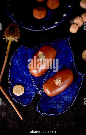 Gâteau de pommes de terre au chocolat avec de la poudre d'or sur le bleu profond de la plaque. Une œuvre d'art culinaire Banque D'Images
