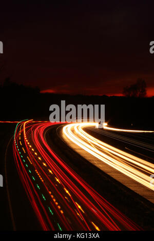 Location de light trails de nuit sur l'autoroute dans le coucher du soleil Banque D'Images