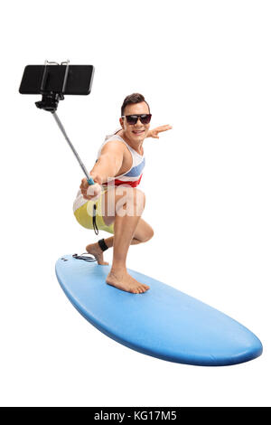 Jeune homme surf et prendre une avec un bâton selfies isolé sur fond blanc Banque D'Images