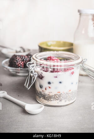 Petit-déjeuner sain dans un bocal en verre avec du yogourt, chia seeds et le gruau sur table, vue avant Banque D'Images