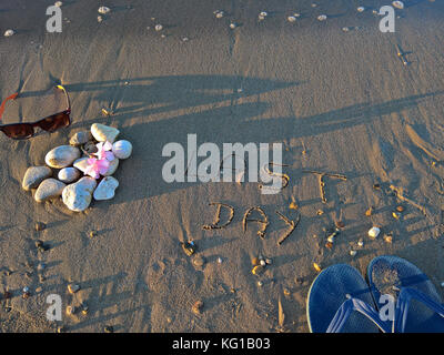 Lunettes de soleil et des chaussons chaussures sur la plage avec des pierres Banque D'Images