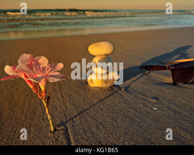 Lunettes de soleil et des chaussons chaussures sur la plage avec des pierres Banque D'Images