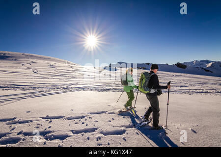 Couple est des randonnées en raquettes à travers les montagnes d'hiver alpin au coucher du soleil. La Bavière, Allemagne. Banque D'Images