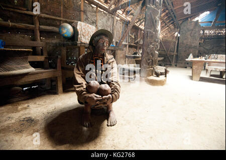 Homme Naga, Longsha Wangnao, chasseur de tête, avec visage tatoué et collier Naga, assis dans la maison tribale communale Naga, Longwa, Nagaland, Inde, Asie Banque D'Images