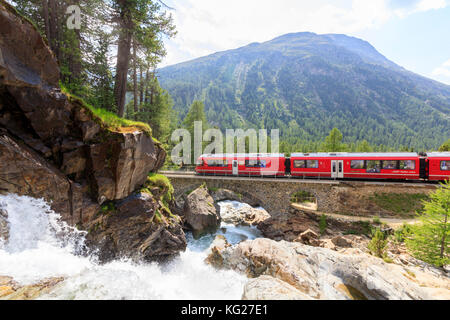 Train Bernina Express à côté du ruisseau alpin, de l'Engadine, morteratsch, canton de Grisons, Suisse, Europe Banque D'Images