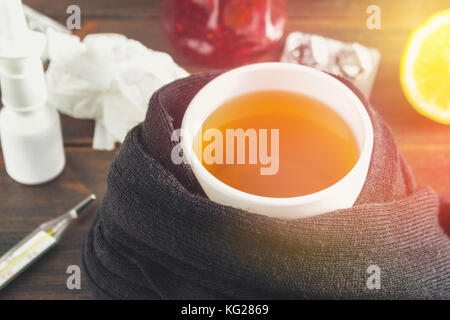 Santé, médecine traditionnelle et concept de la grippe - tasse de thé au citron, thermomètre et des drogues sur table en bois Banque D'Images