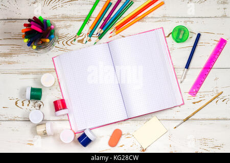 Ordinateur portable en plein air entouré par les fournitures scolaires sur un fond en bois blanc, avec l'espace vide pour des inscriptions Banque D'Images