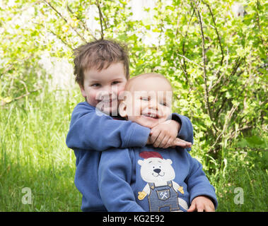 Deux petits frères heureux de jouer à l'extérieur l'été. le frère aîné hugging young Banque D'Images