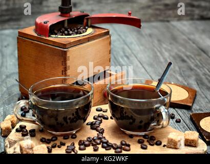 Deux tasses de café grains de café,brun,sucre forfaitaire et rectifieuse de café sur fond de bois. Banque D'Images