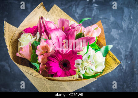 Bouquet de fleurs de lys, gerbera, roses blanches et l'alstroemeria contre l'arrière-plan d'un mur de béton foncé. une maison de vacances, un cadeau. Banque D'Images