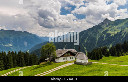 Vieux chalet en bois et chapelle en matschwitz avec en arrière-plan les montagnes de montafon sur un été, Autriche Banque D'Images