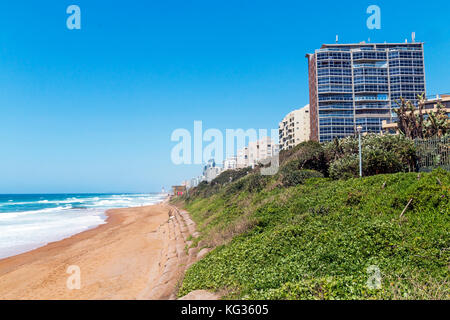 Paysage côtier de vert la végétation des dunes de sable et de la mer contre les bâtiments commerciaux et résidentiels et ciel bleu à umhlanga près de Durban en af du sud Banque D'Images