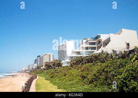 Paysage côtier de vert la végétation des dunes de sable et de la mer contre les bâtiments commerciaux et résidentiels et ciel bleu à umhlanga près de Durban en af du sud Banque D'Images