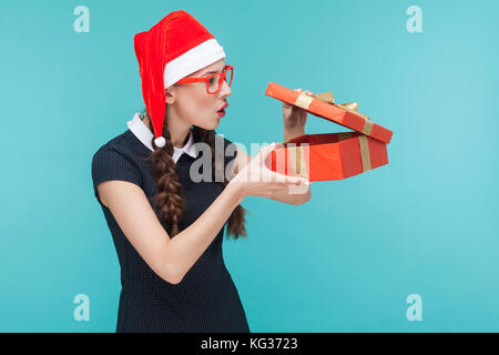 Cunning businesswoman looking at boîte-cadeau et que vous souhaitez ouvrir. trop fond bleu. studio shot Banque D'Images