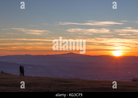 Un couple à la recherche au coucher du soleil depuis le sommet d'une montagne Banque D'Images
