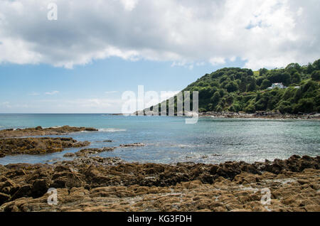 Une vue sur la mer d'une côte rocheuse dans la baie de Tland avec une maison sur la colline au loin. Banque D'Images