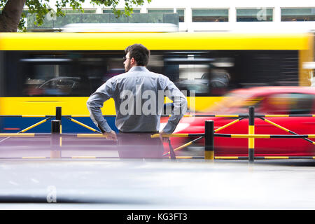 Belgrade, Serbie - 21 juin 2017 : un jeune homme attendant à l'arrêt de bus s'est appuyé sur les rampes au milieu de la rue, avec la circulation urbaine en arrière-plan Banque D'Images