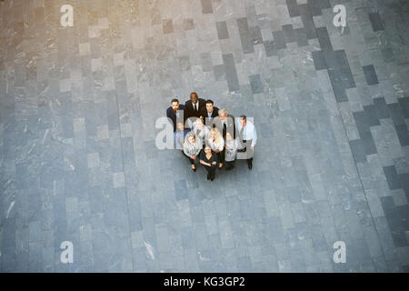 High angle portrait d'une équipe diversifiée de collègues souriants jusqu'à debout ensemble dans le hall d'un immeuble de bureaux modernes Banque D'Images