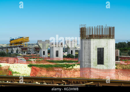 La construction d'un pont ou d'autoroute Autostrada avec grande grue à portique levage en sections de route entre piliers. la Sicile, Italie Banque D'Images