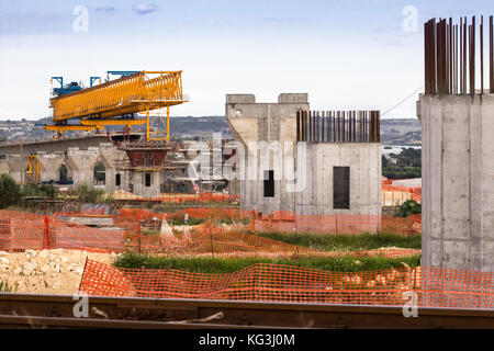 La construction d'un pont ou d'autoroute Autostrada avec grande grue à portique levage en sections de route entre piliers. la Sicile, Italie Banque D'Images