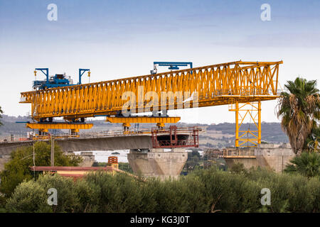 La construction d'un pont ou d'autoroute Autostrada avec grande grue à portique levage en sections de route entre piliers. la Sicile, Italie Banque D'Images