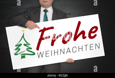 Frohe weihnachten (en allemand) joyeux noël poster est tenu par l'homme d'affaires. Banque D'Images
