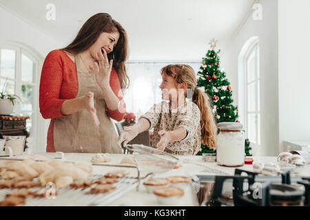 Mère et fille jouer avec cookie farine à table de cuisine tout en faisant des biscuits de Noël. Petits gâteaux et muffins sur la table de cuisine de Chri Banque D'Images