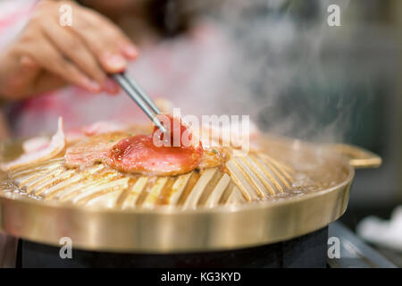 Hand holding baguette avec des grillades de porc coréen yakiniku grillé style japonais. Banque D'Images