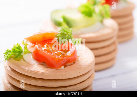 Sur des craquelins légumes : tomates, fromage et les verts de persil. close up, faible profondeur de la netteté Banque D'Images