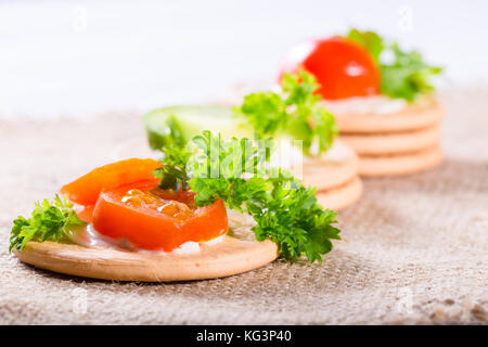 Des légumes sur des craquelins : morceaux de tomate et le persil. close up, faible profondeur de la netteté Banque D'Images