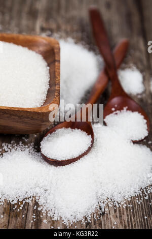 Le sucre dans un bol en bois et deux cuillères sur un vieux fond de bois. Banque D'Images