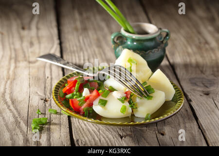 De pommes de terre bouillies avec tomates et oignons verts. Un plat sur une table à partir d'anciennes cartes. style rural, Close up, selective focus Banque D'Images