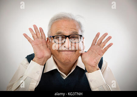 Old man making funny face avec les mains dans ses oreilles Banque D'Images