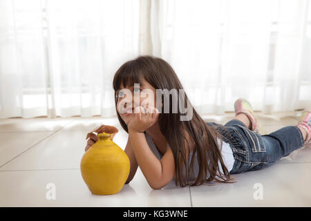 Petite fille de pensée avec piggy bank Banque D'Images