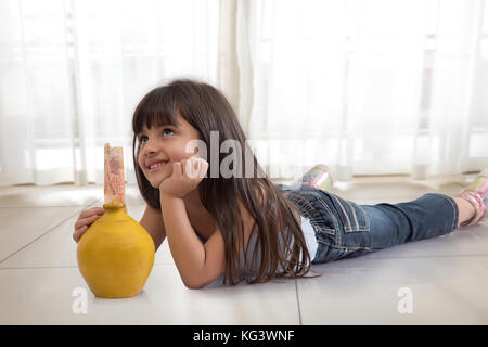 Petite fille de pensée avec piggy bank Banque D'Images