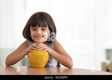 Portrait of smiling little girl holding piggy bank d'argile Banque D'Images