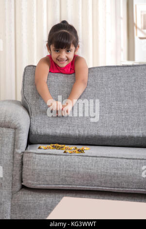 Petite fille s'appuyant sur canapé avec des bonbons au chocolat Banque D'Images