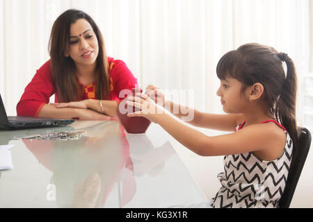 Mère et fille de putting coins in piggy bank Banque D'Images