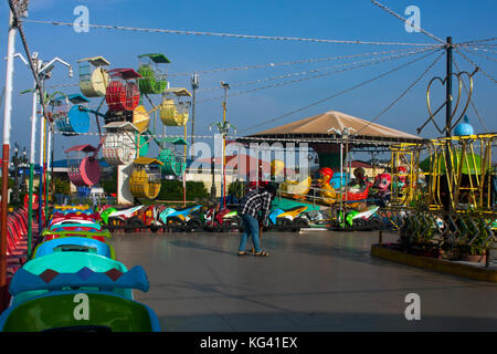 Une jeune femme asiatique balaie un sol dans une zone de manège près d'une grande roue dans un parc d'attractions sur l'île de Ko Pech à Phnom Penh, au Cambodge. Banque D'Images