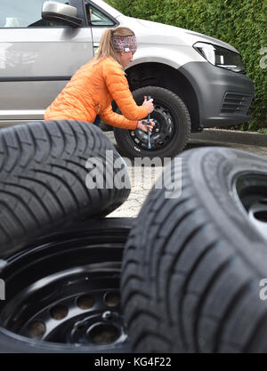 Garmisch-Partenkirchen, Allemagne. 04th Nov, 2017. ILLUSTRATION - Une jeune femme change les pneus de sa voiture à Garmisch-Partenkirchen, Allemagne, 04 novembre 2017. Crédit : Angelika Warmuth/dpa/Alamy Live News Banque D'Images