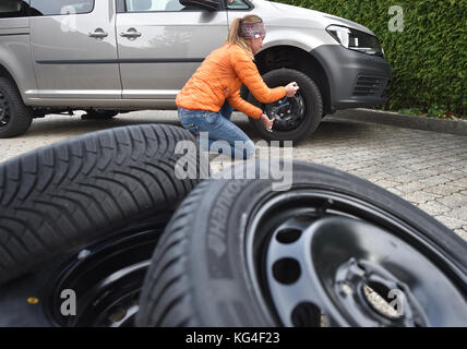 Garmisch-Partenkirchen, Allemagne. 04th Nov, 2017. ILLUSTRATION - Une jeune femme change les pneus de sa voiture à Garmisch-Partenkirchen, Allemagne, 04 novembre 2017. Crédit : Angelika Warmuth/dpa/Alamy Live News Banque D'Images
