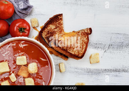 Soupe de tomate chaud avec du parmesan et croûtons servis avec un sandwich au fromage. image en plongée des mises à plat dans le style. Banque D'Images