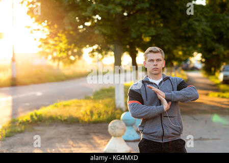 Warm-up Hands, un jeune mec runner tôt le matin faire le casque. Un homme dans le parc à l'écoute de la musique, un certain regard. En été, le style de vie, Banque D'Images