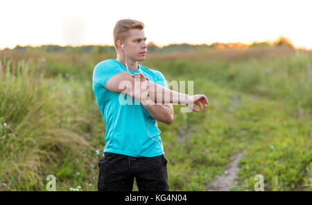 Un entraîneur masculin pétrit ses mains avant la formation d'un casque. Runner matin dans parc. Écoute de la musique et confiant. Vie d'été, la motivation est st Banque D'Images