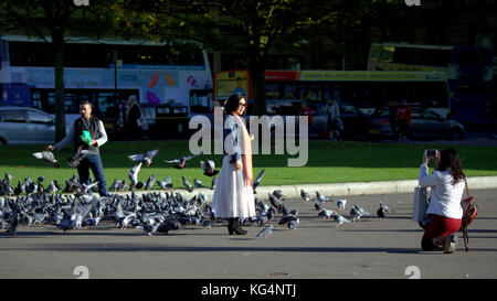 Les touristes prendre des autoportraits car les pigeons nourris par un étranger à george square Glasgow Banque D'Images