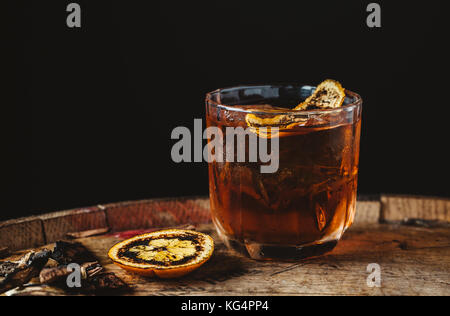 Cocktail old fashioned fumé garni d'une pelure d'orange sur fond de bois foncé Banque D'Images