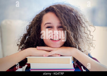 Portrait of teen girl reposant sur les livres dans la chambre Banque D'Images