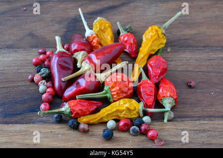 Hot epices, tas de frais et sec mixte, piments rouges et jaunes et rouges, de poivre noir et blanc sur fond de bois foncé Banque D'Images