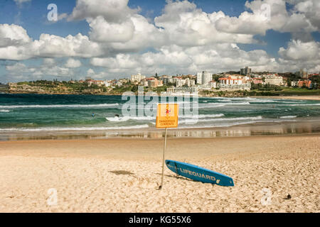 Surf bleu contre yellow dog signe sur la célèbre plage de Bondi) (Bondai beach, Sydney New South Wales Australie sous ciel dramatique. Banque D'Images