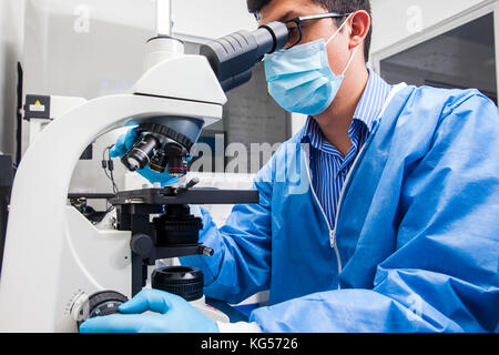 Young male scientist looking at glisse sous le microscope Banque D'Images
